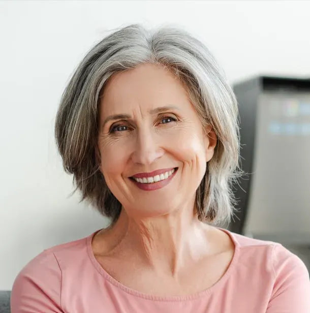 Smiling mature woman with gray hair wearing pink top, natural beauty and confidence